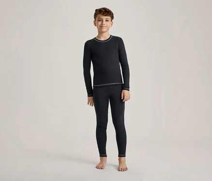 Ein Junge steht barfuß und trägt ein dunkelblaues Langarmshirt und passende Leggings mit hellen Nähten.