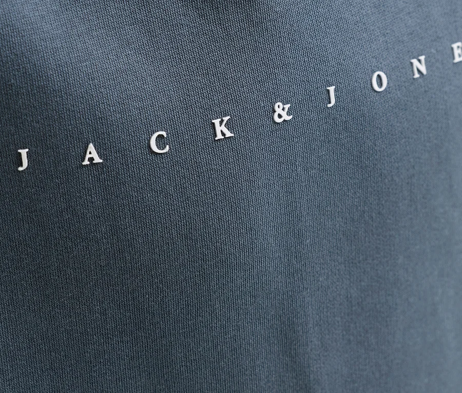 Dunkelgrauer Jack&Jones Sweat-Hoodie Star mit weissem Schriftzug "JACK & JONE" diagonal auf dem Stoff.