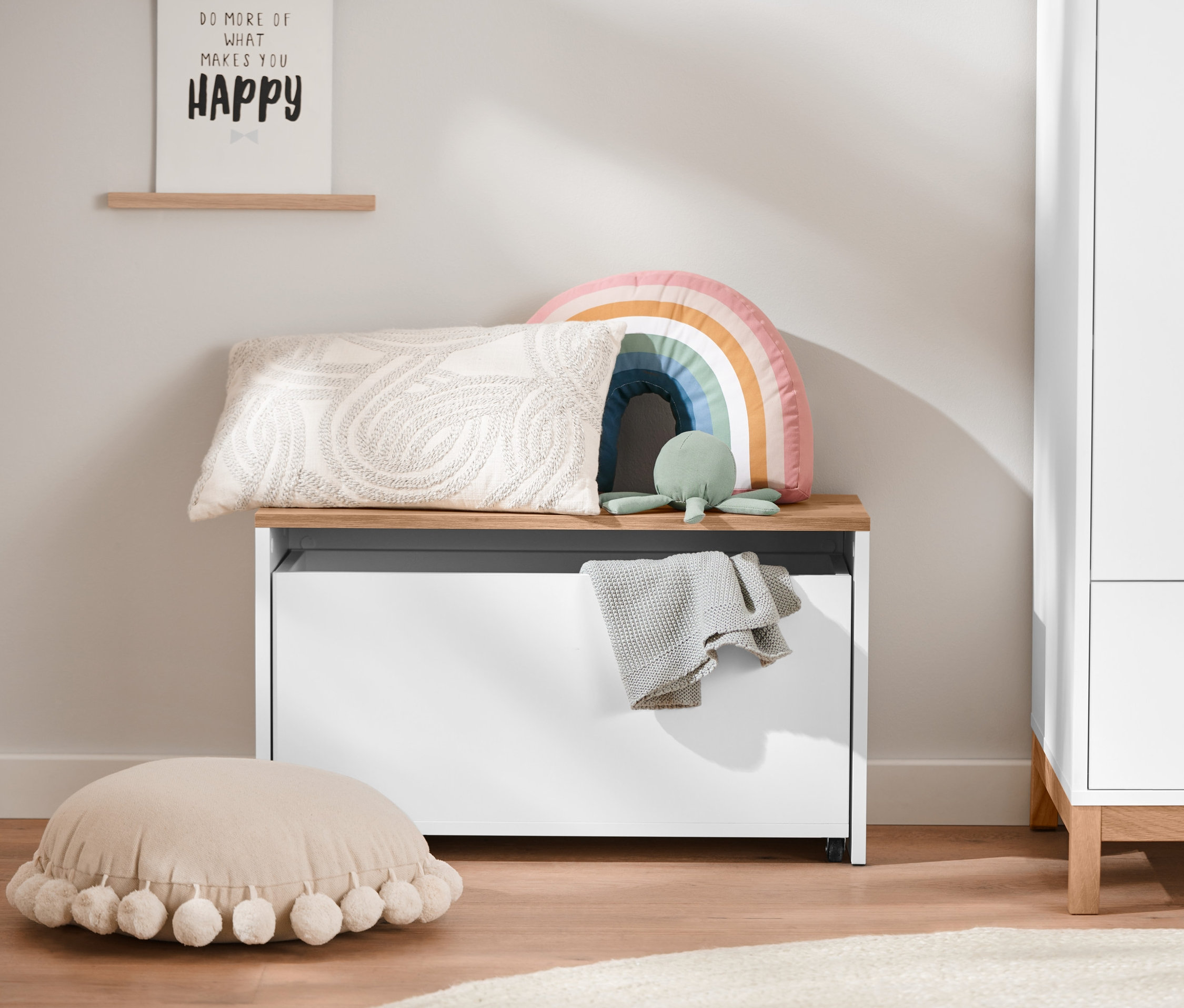 Auf einer Sitzbank mit Stauraum-Box liegen ein Kissen, ein Plüsch-Regenbogenkissen und ein Schildkrötenspielzeug.