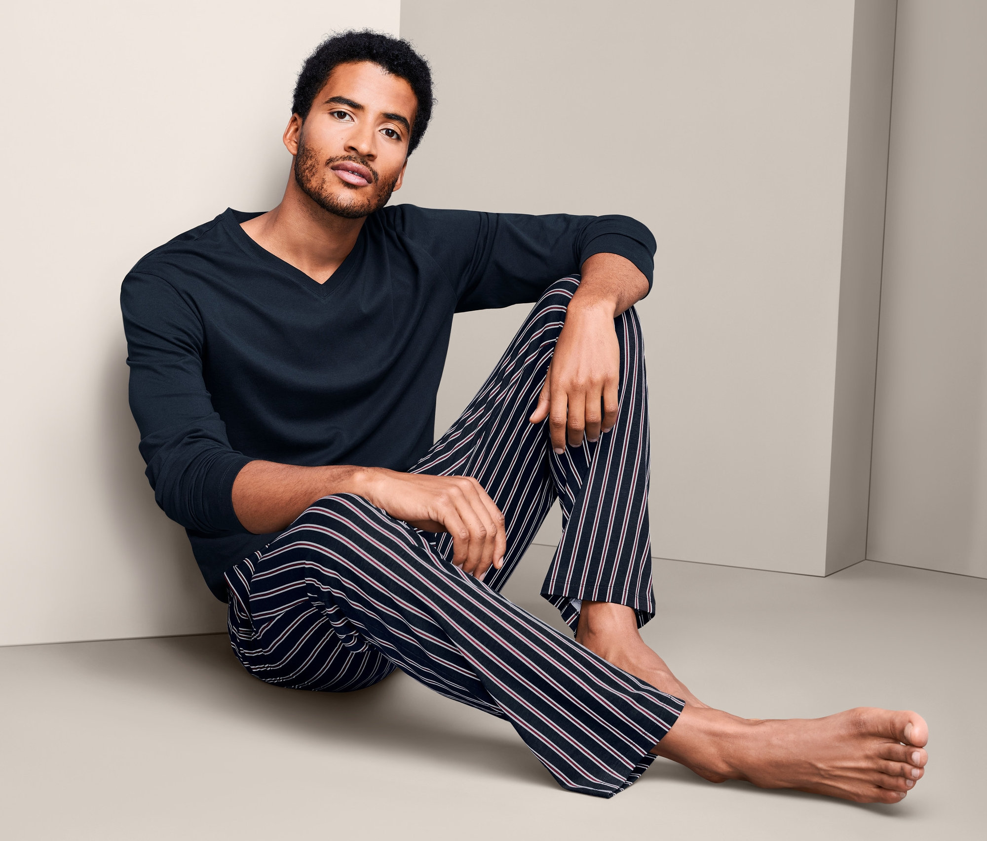 Mann sitzt mit Pyjama am Boden.