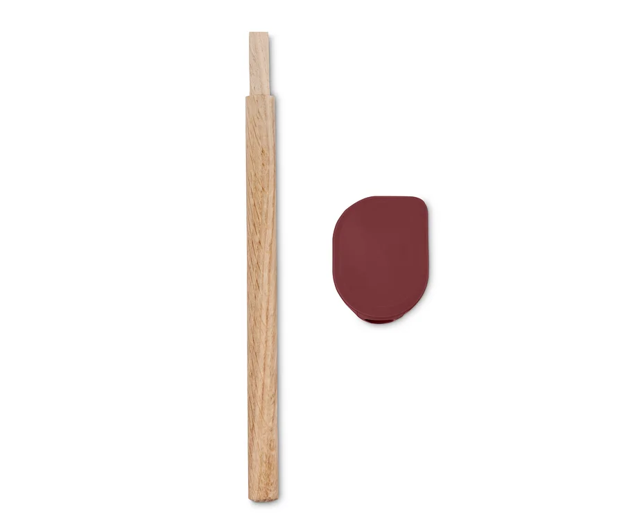 Ein Holzgriff und ein bordeauxroter Silikonspatel liegen nebeneinander auf einem weißen Hintergrund.