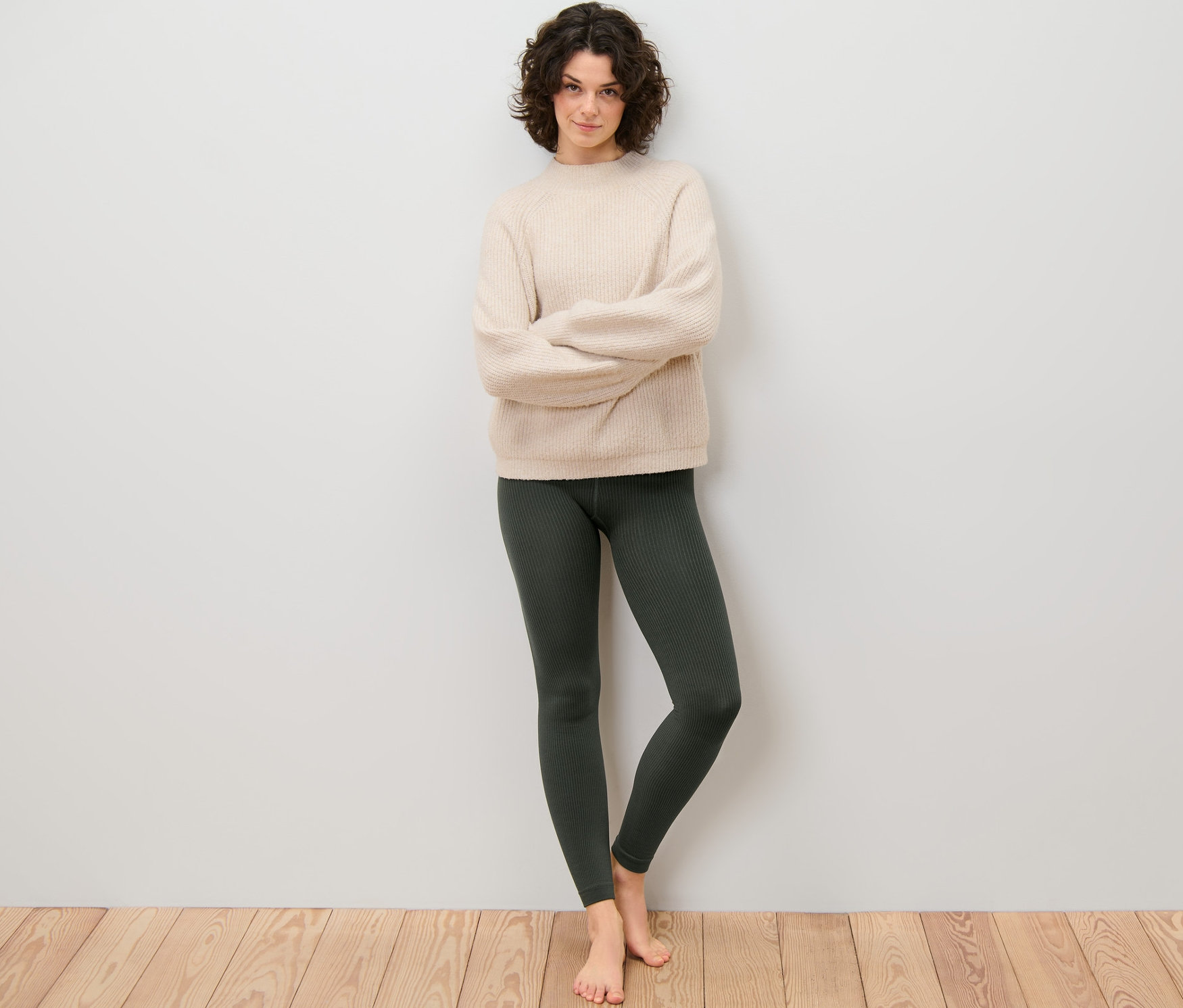 Frau steht mit verschränkten Armen und trägt eine gerippte Thermoleggings.