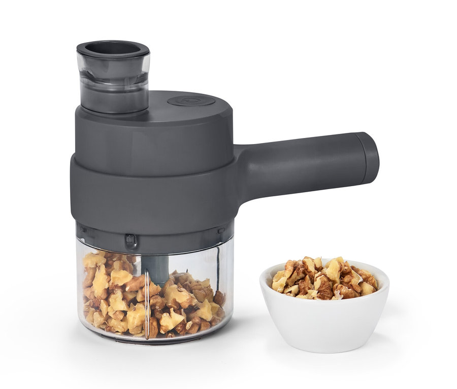 Ein Akku-Multizerkleinerer mit Nüssen im Behälter und einer Schüssel.