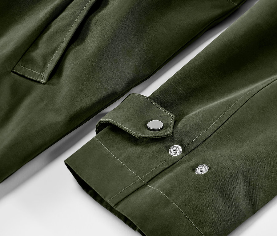 Detailansicht einer grünen Parka mit Tasche und Ärmel mit silbernen Druckknöpfen.
