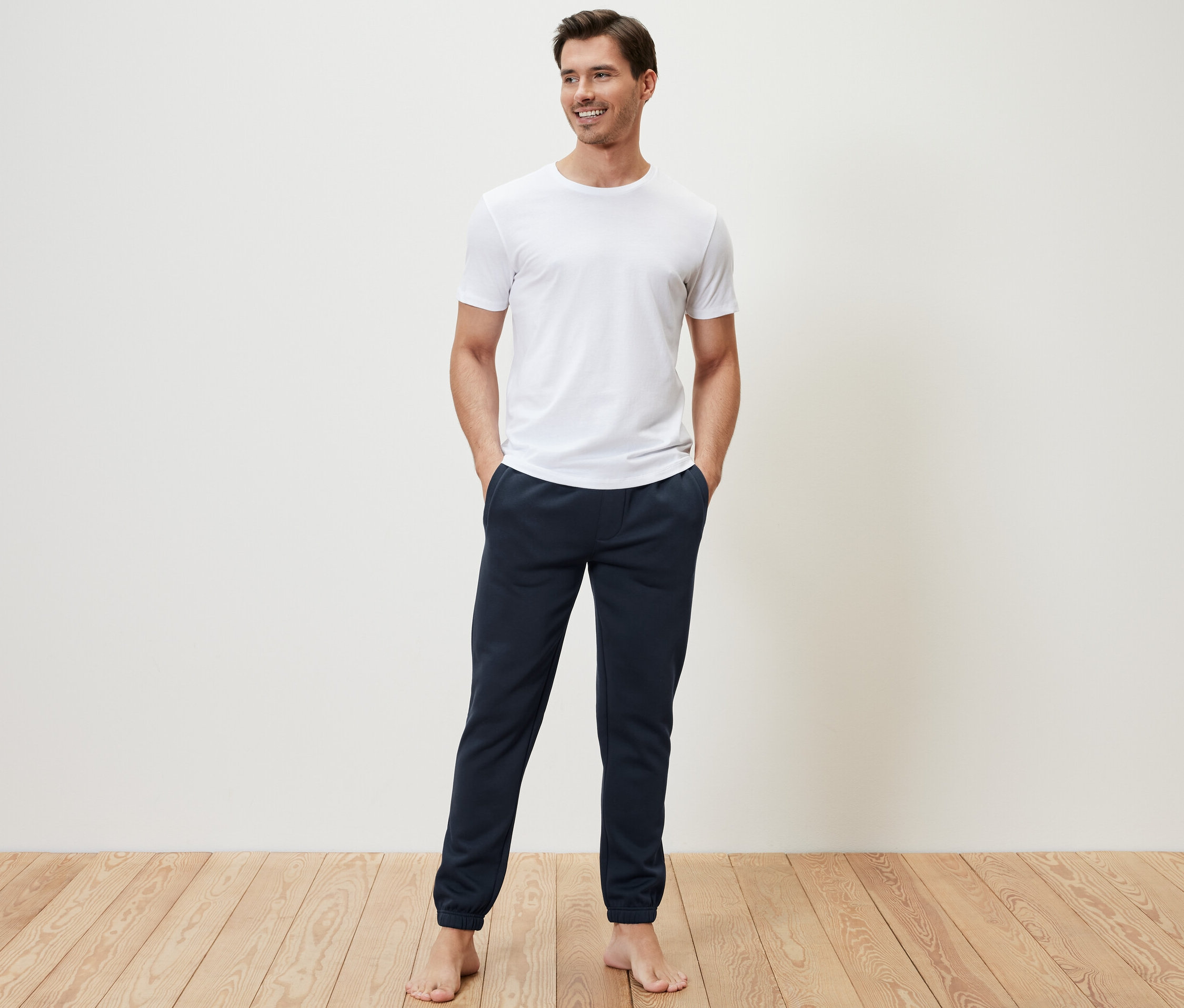 Mann steht mit Händen in den Taschen der Sweathose.