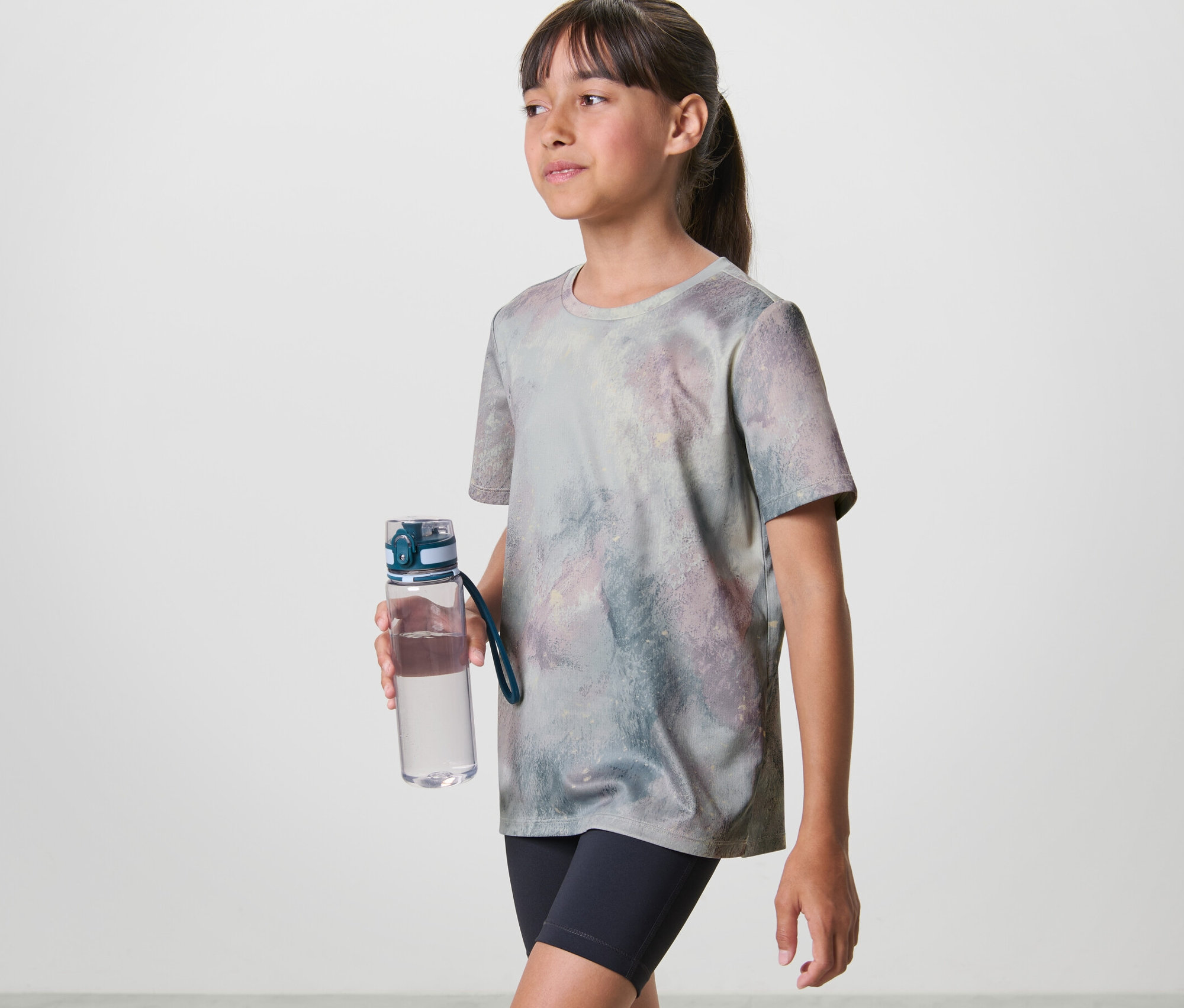 Mädchen mit Trinkflasche trägt ein Kinder-Sportshirt (2 Stk).