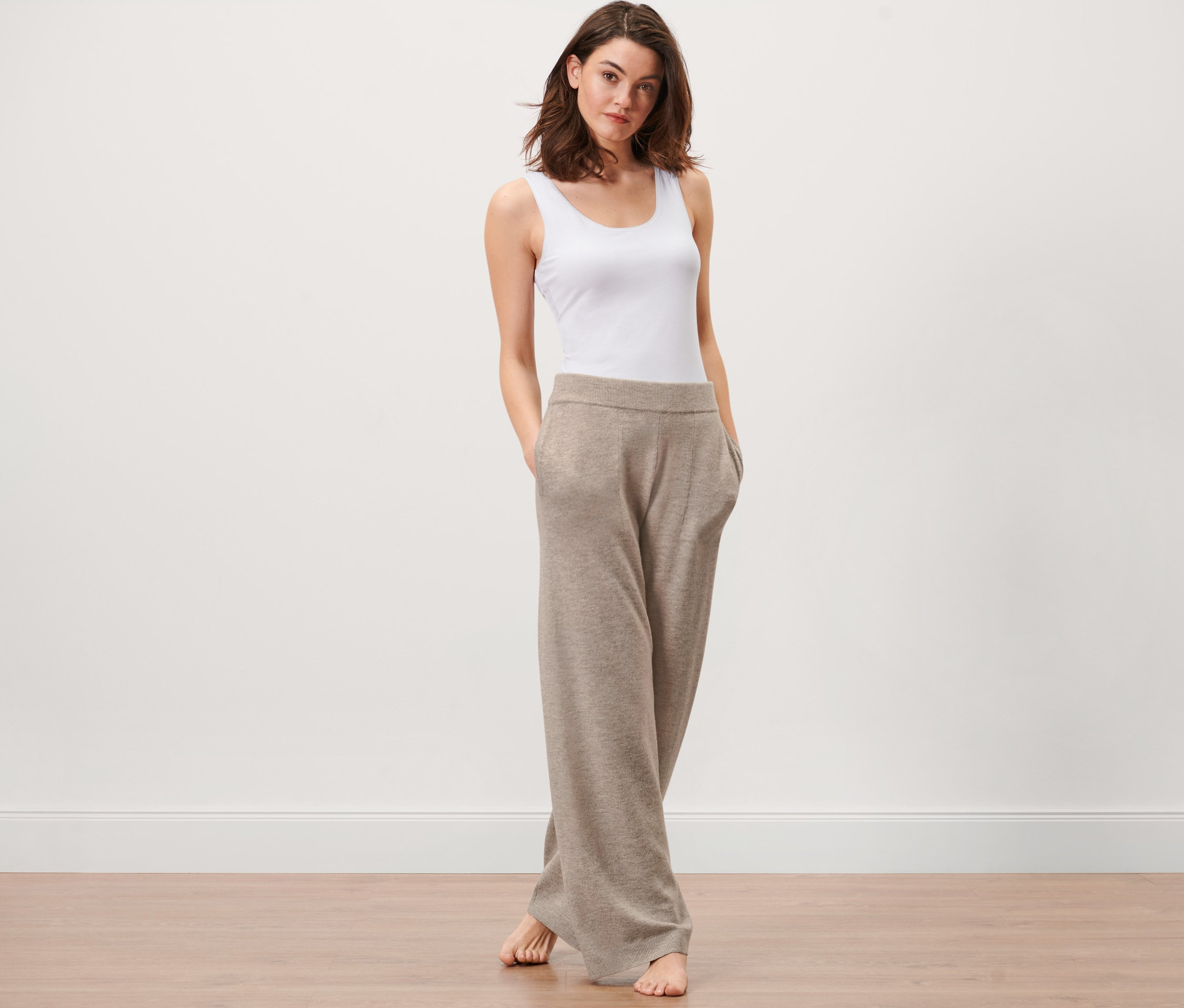 Frau steht mit Händen in den Taschen einer Lounge-Hose aus Strick.
