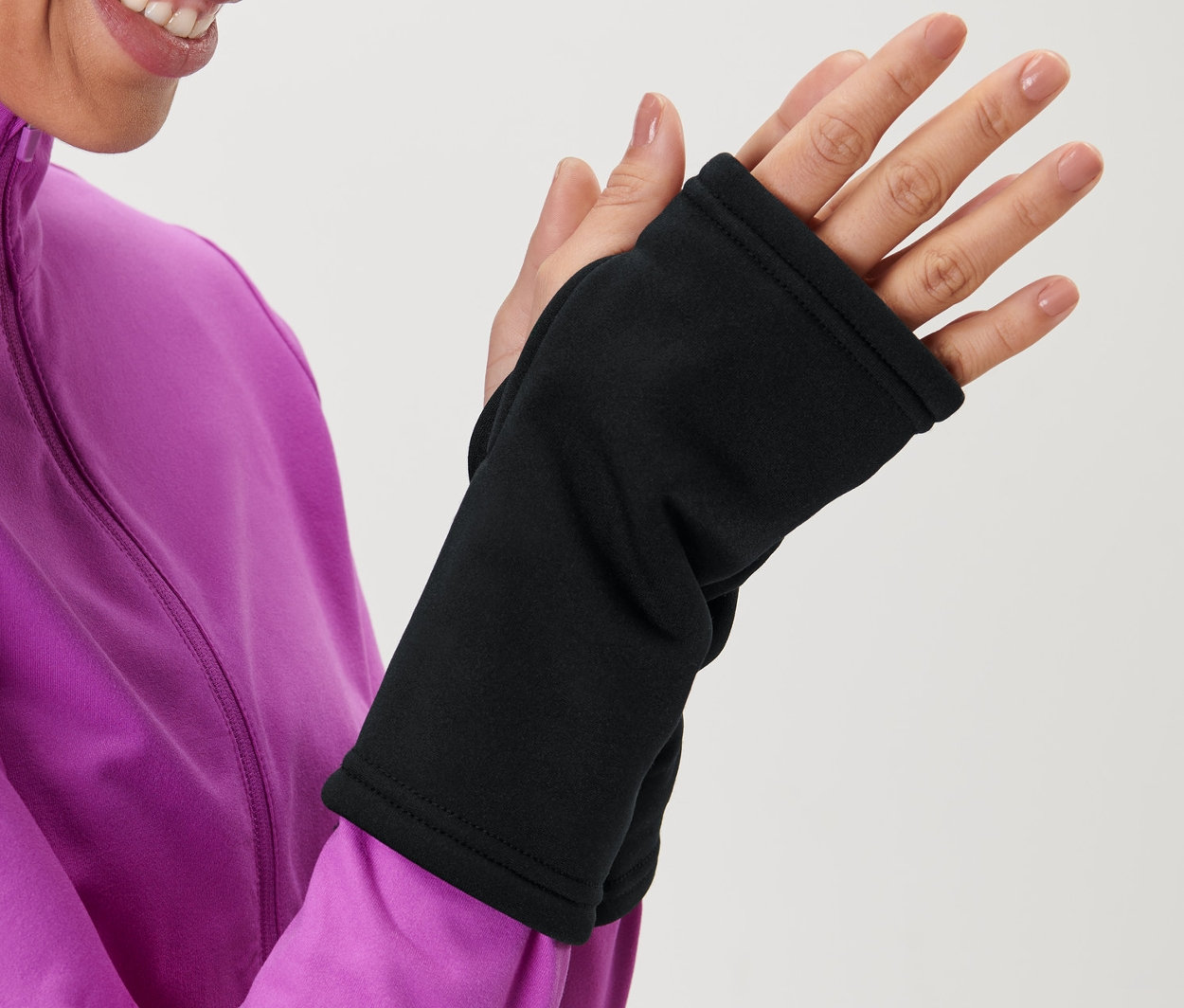 Frau in pinker Jacke zieht schwarze Handstulpen an.