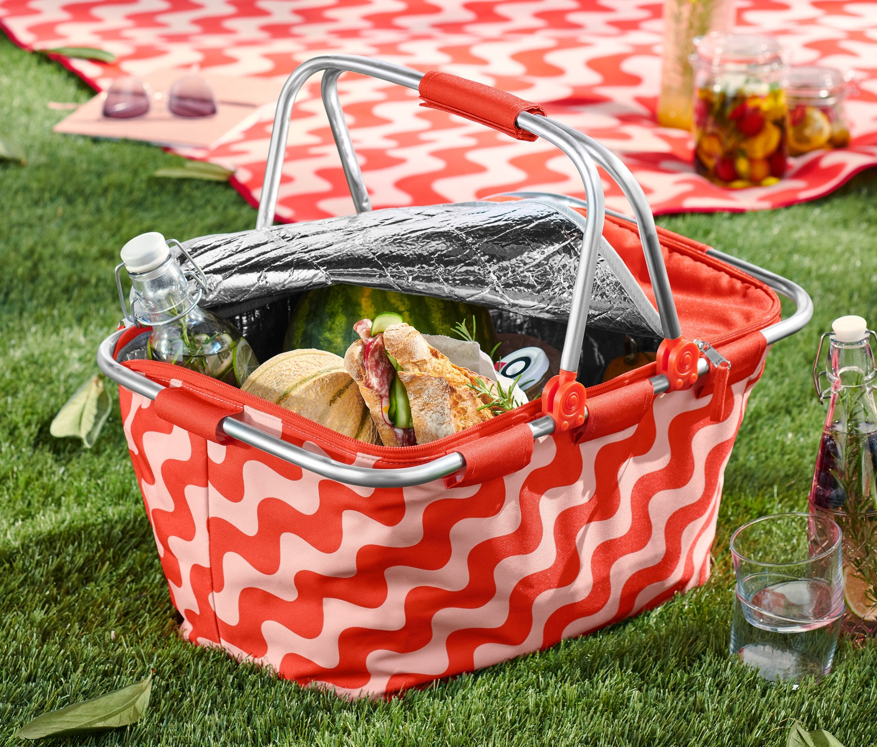 Ein Kühlkorb mit Essen und Trinken steht auf einer Wiese.