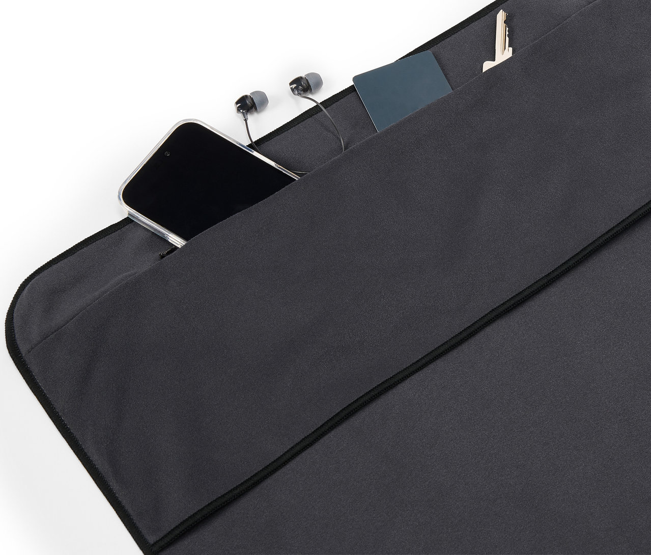 In der Tasche aus schwarzem Stoff liegen ein Handy, Kopfhörer, eine Karte und ein Schlüssel.