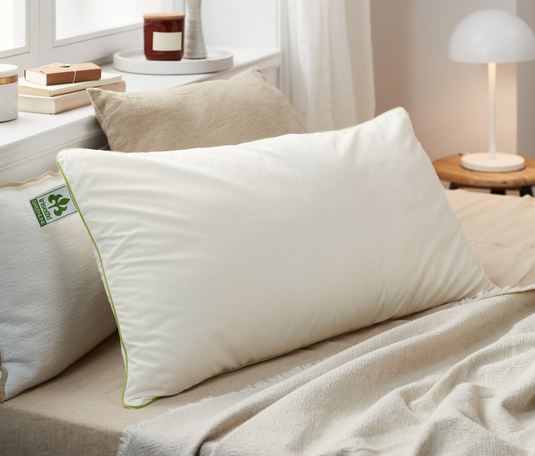 Mehrere irisette® greenline Federkopfkissen in verschiedenen Größen liegen auf einem Bett.