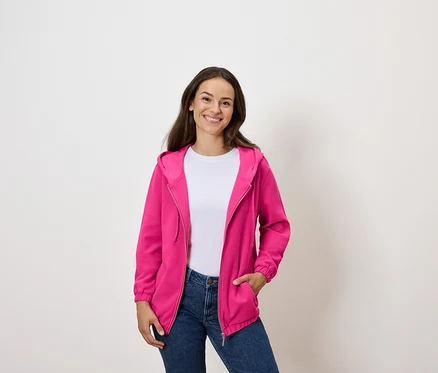 Frau trägt eine fuchsiafarbene Sweatjacke über einem weißen T-Shirt und Jeans.