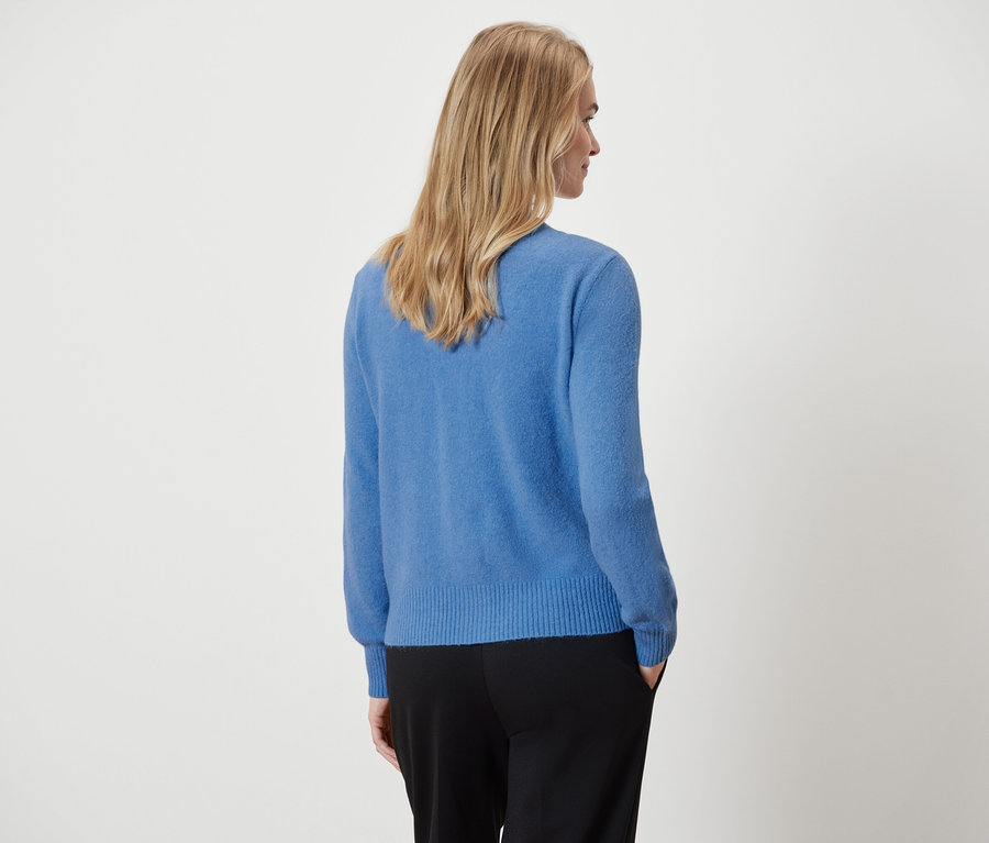 Abgebildete Frau von hinten, trägt einen blauen Pullover und eine schwarze Hose.