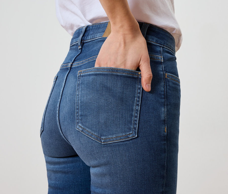 Frau mit Hand in der Gesäßtasche von blauen Jeans.