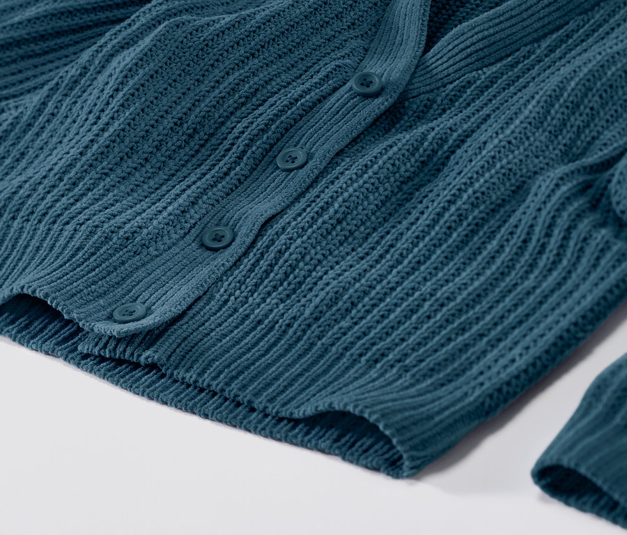 Nahaufnahme einer petrolfarbenen Strickjacke mit Knöpfen.