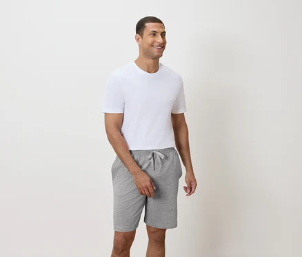 Ein Mann trägt ein weißes T-Shirt und graue Shorts.