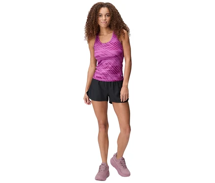 Frau mit lockigem Haar trägt ein lila Tanktop, schwarze Shorts und lila Turnschuhe.