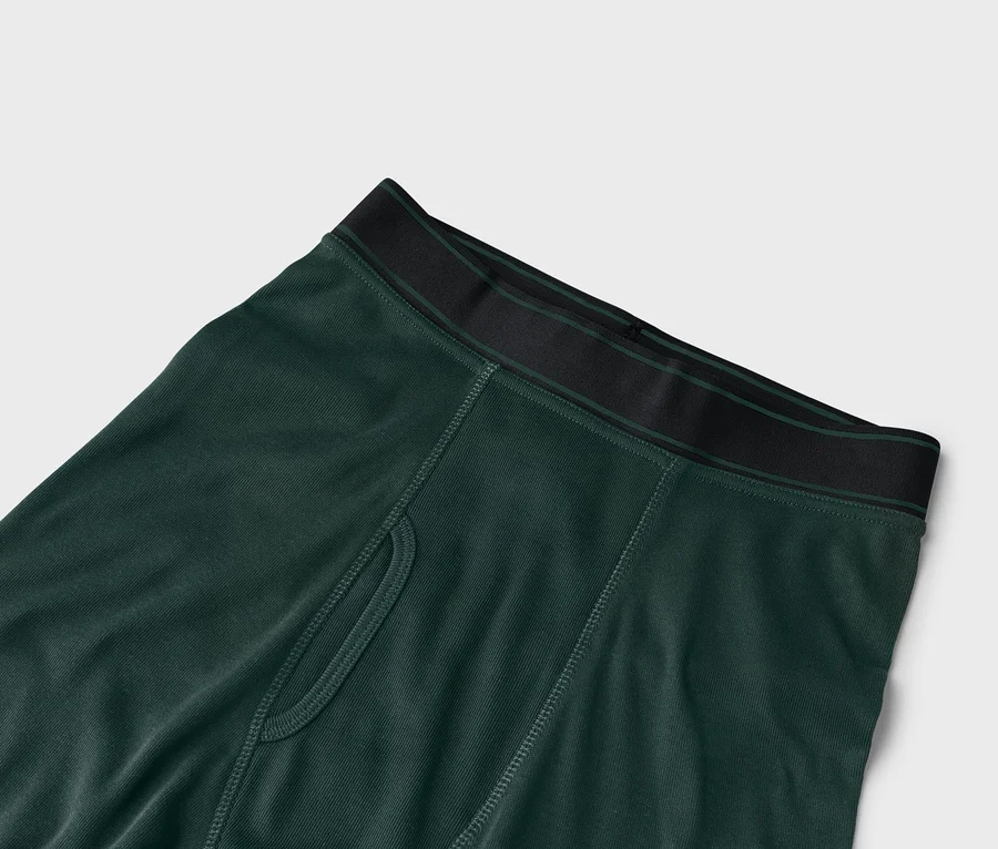 Nahaufnahme einer grünen Boxershorts mit schwarzem Bund auf einem weißen Hintergrund.