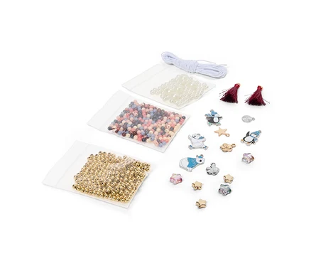 Bastelset mit drei Beuteln Perlen (goldfarben, mehrfarbig, weiß), weißer Schnur, zwei roten Quasten und verschiedenen Anhängern wie Pinguinen, Eisbären, Sternen und Blumen.