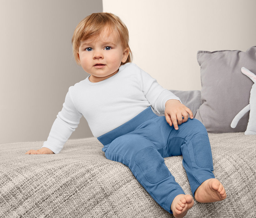 Ein Kind sitzt auf einem Bett und trägt eine 2 Baumwoll-Sweat-Schlupfhose.