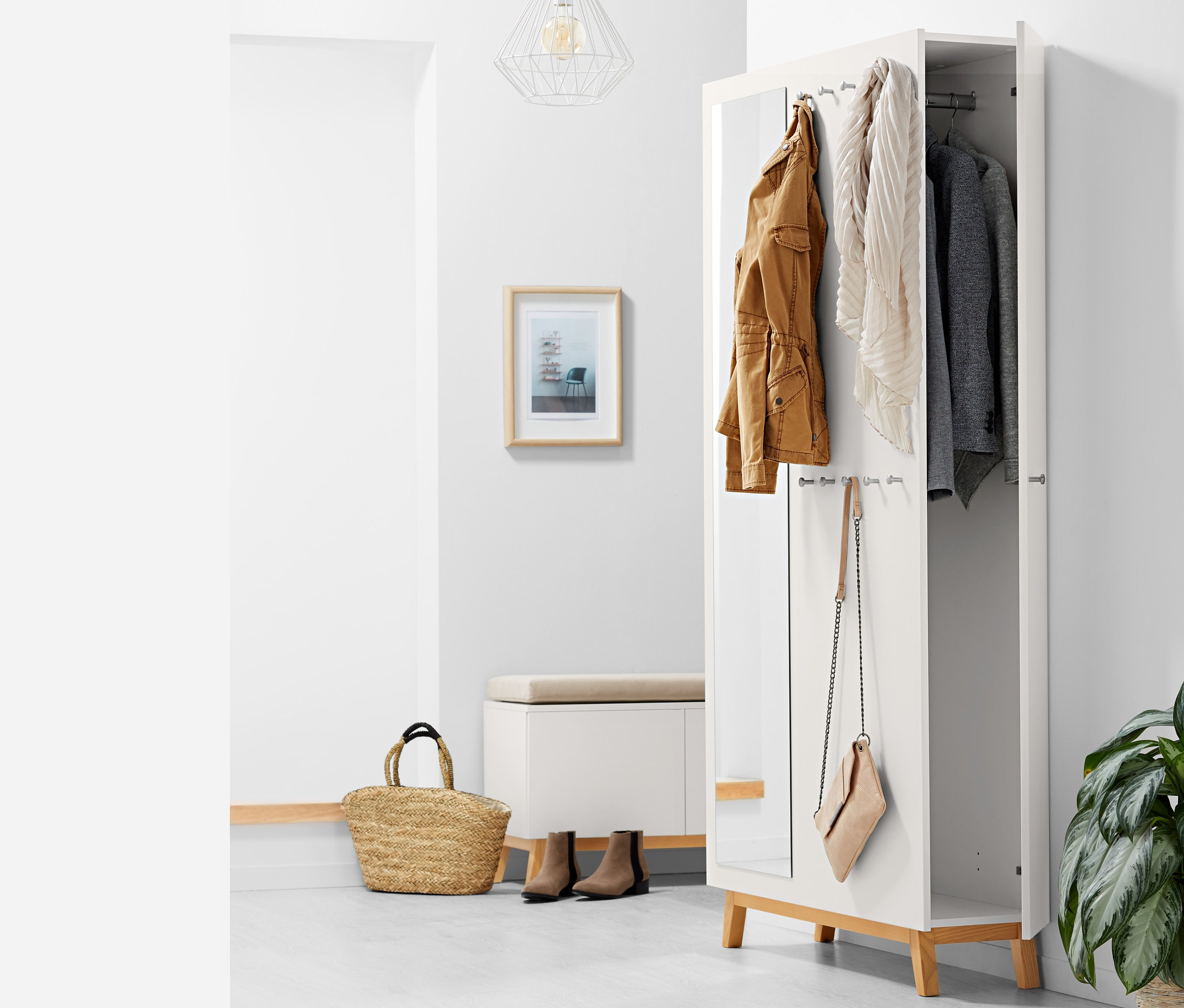 Offener multifunktionaler Flurschrank mit brauner Jacke, Schal und grauem Sakko im Inneren, eine Handtasche hängt an der Seite.