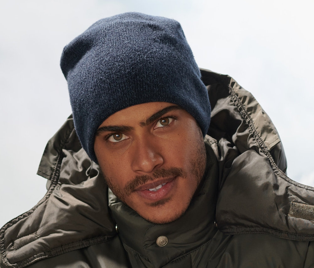 Mann sitzt auf Bank mit dunkelblauer Strickmütze.