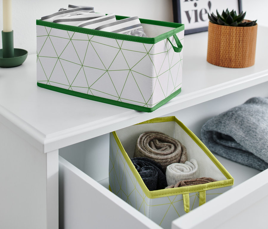 Zwei mittlere Schubladen-Ordnungsboxen, eine auf der Oberseite einer Kommode und die andere in einer offenen Schublade mit aufgerollter Kleidung.