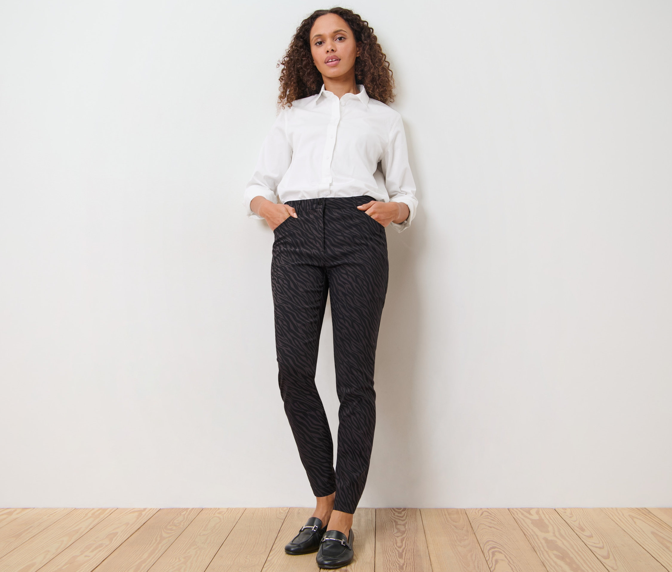 Frau posiert in bedruckter Bengalin-Hose und weißem Hemd.