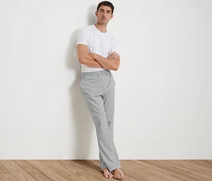 Mann lehnt an Wand, trägt weißes T-Shirt und Homewearhose.