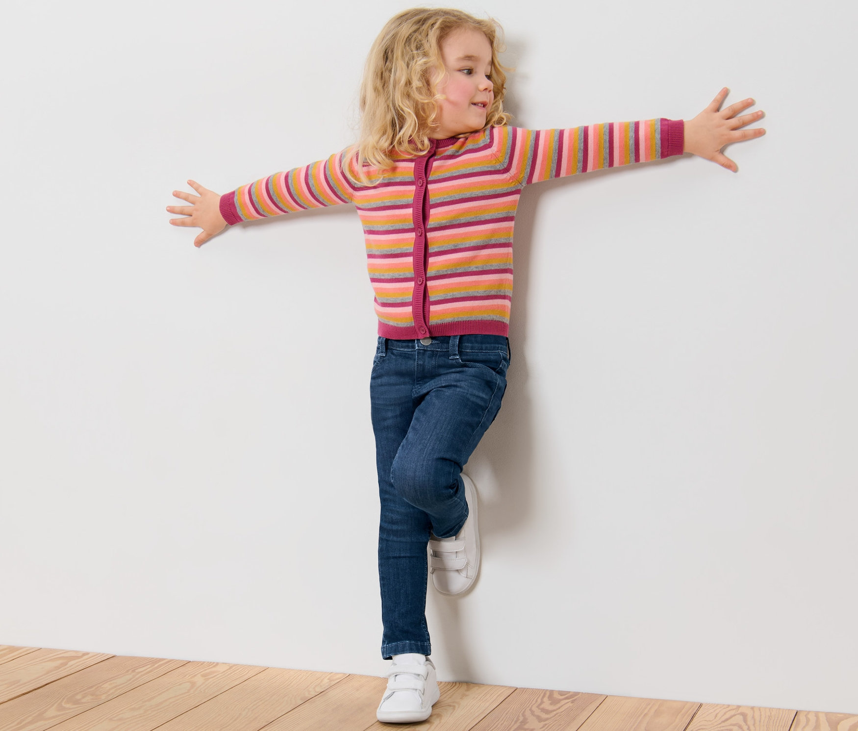 Mädchen lehnt in Kinder-Jeans ‒ Fit »Lotta« an einer weißen Wand.