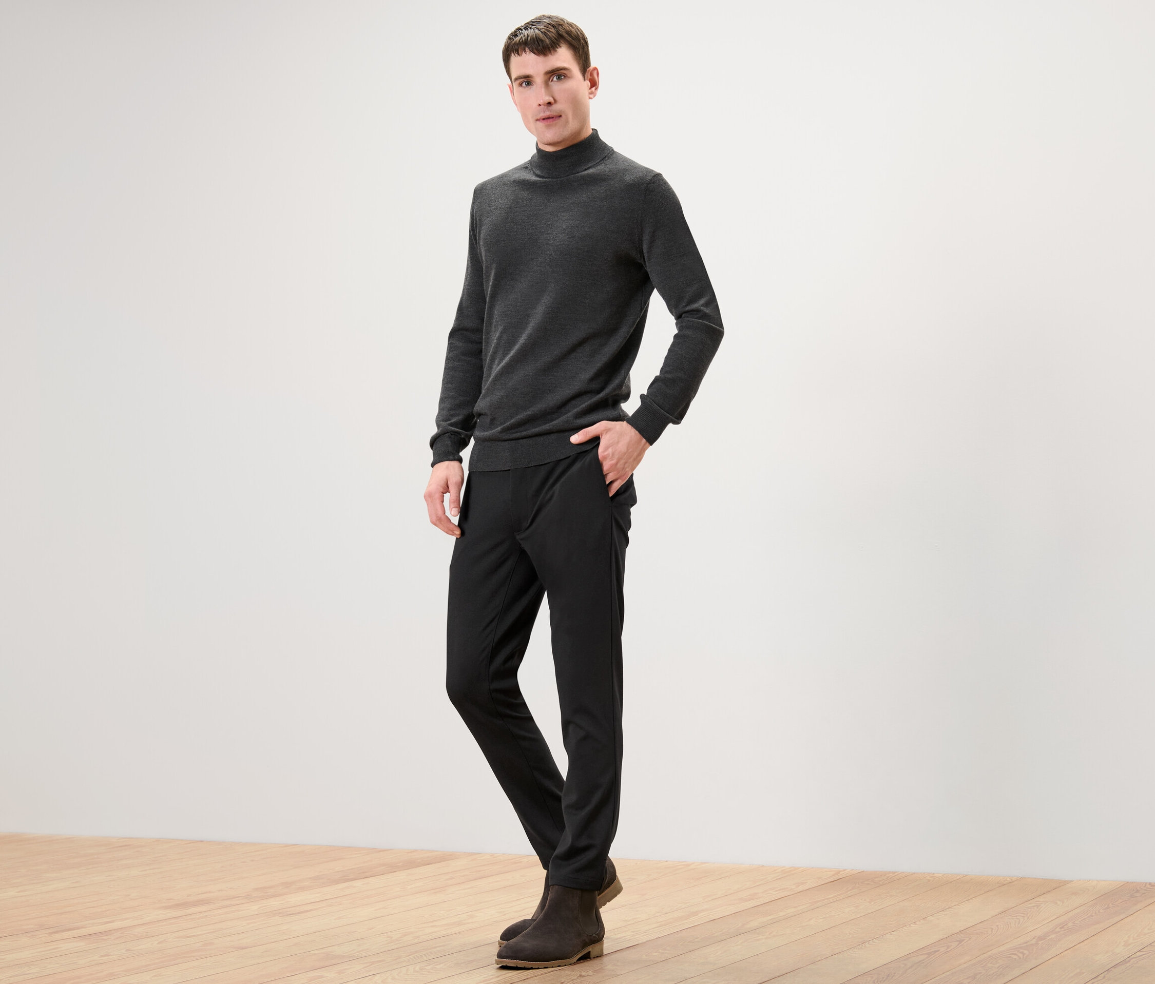 Ein Mann posiert in einer schwarzen Comfort-Stretch-Hose für die Kamera.