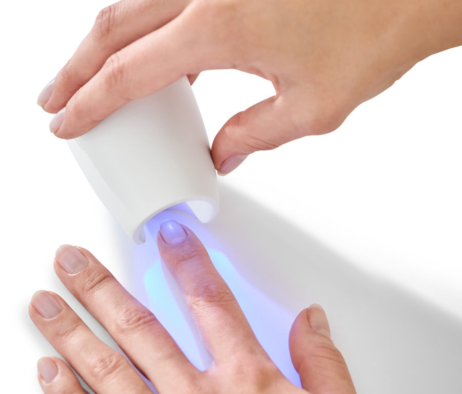 Frau verwendet UV-Lampe aus 5-in-1-Maniküre-Pediküre-Set.