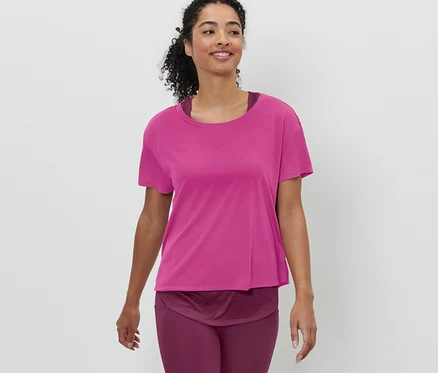 Frau trägt ein pinkes 2-in-1-Kurzarm-Sportshirt und geht.