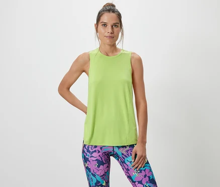 Frau posiert in einem limefarbenen Sport-Top aus einem zweiteiligen Set und gemusterten Leggings.