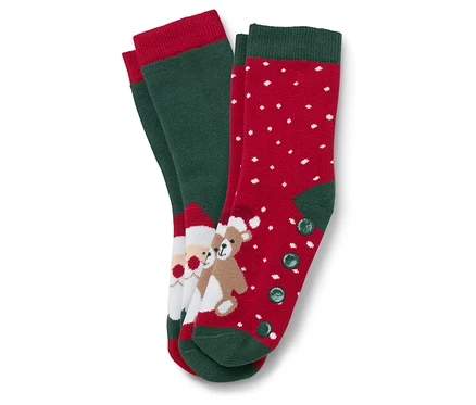 Zwei Paar Weihnachtssocken. Ein Paar ist grün mit rotem Rand und einem Bild von Santa Claus und einem Teddybär. Das andere Paar ist rot mit weißen Punkten und grünem Rand und Knöpfen.