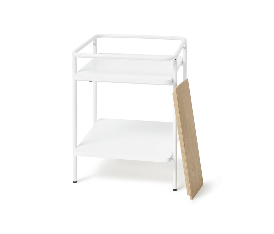 Weißer Beistelltisch mit zwei Ablagen und einer an der Seite angelehnten Holzplatte.
