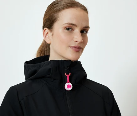 Frau trägt eine schwarze Kapuzenjacke mit pinkem Reißverschluss.