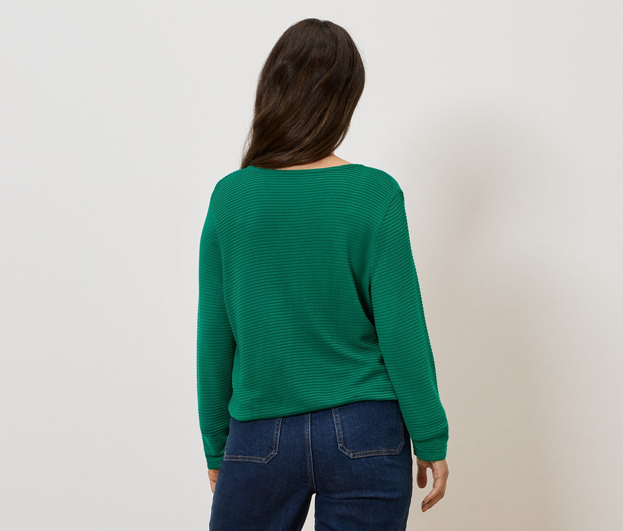 Frau von hinten mit grünem Pullover und Jeans.