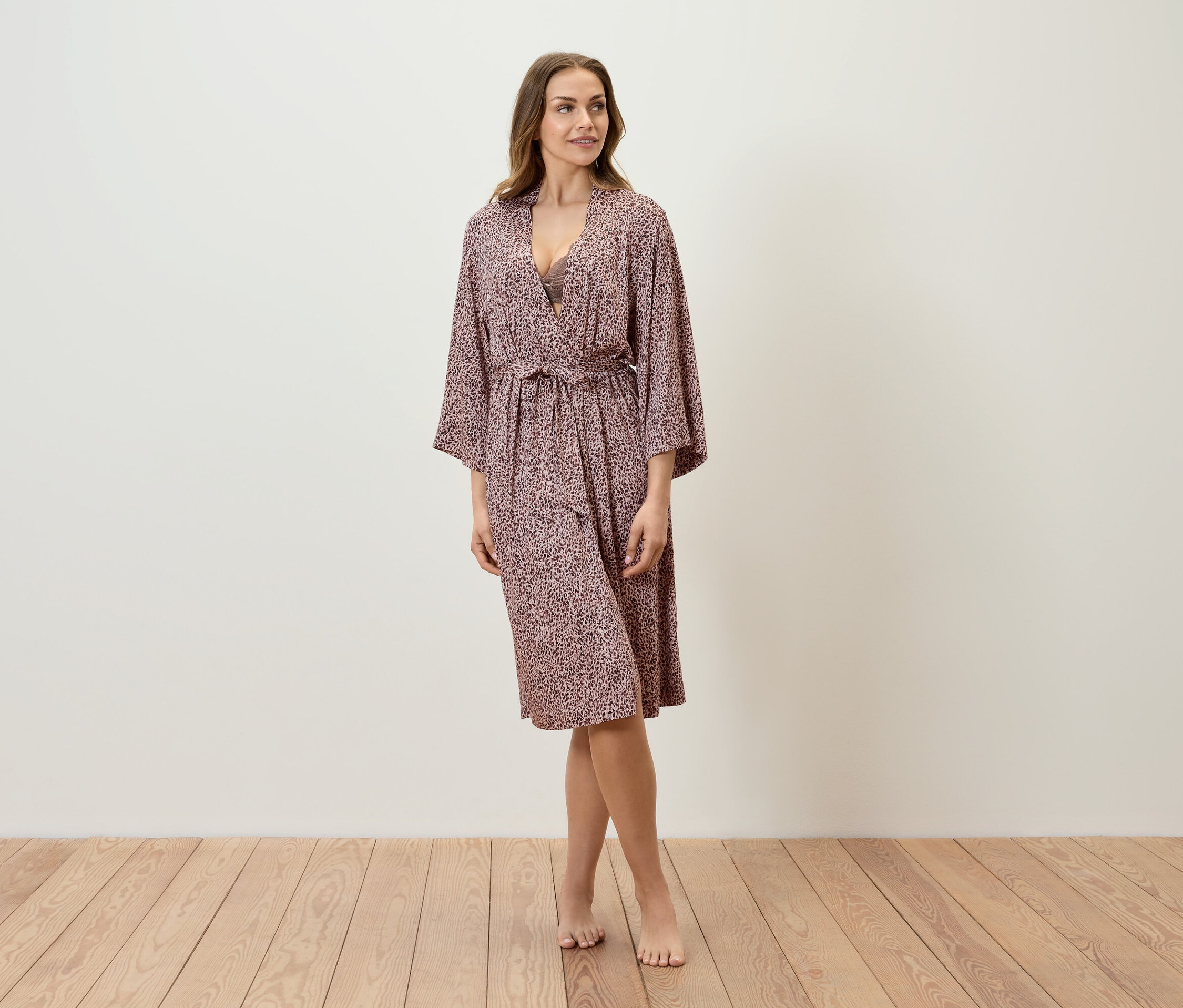 Eine Frau steht auf einem Holzboden und trägt einen gemusterten Bademantel.