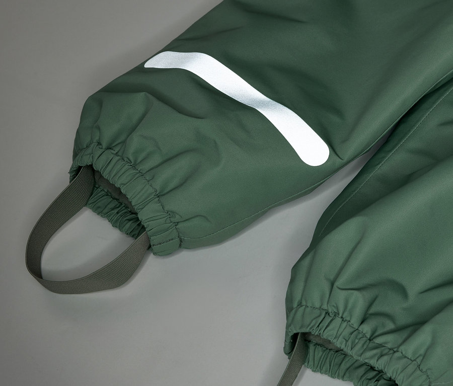 Nahaufnahme einer grünen Regenhose mit elastischen Bündchen und einem reflektierenden Streifen am Bein.