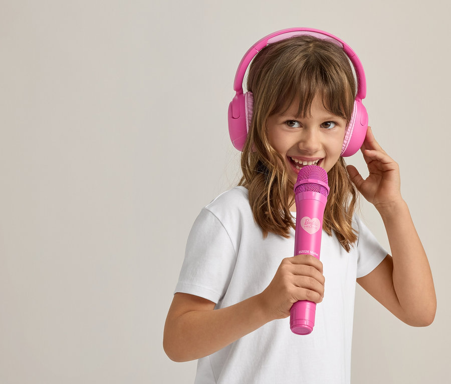 Mädchen mit pinken Kopfhörern und Mikrofon singt.