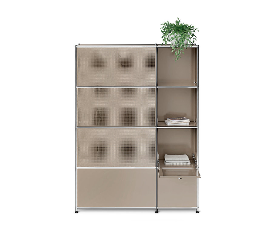 Hellbraunes modulares Regal mit silbernem Rahmen. Links drei perforierte, eine geschlossene Tür. Rechts oben Topfpflanze, mittig Bücher und Handtücher, unten teilweise geöffnete Schublade.