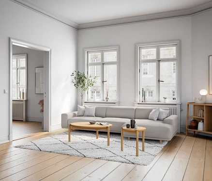 Wohnzimmer mit hellgrauem »Penelope« 2,5-Sitzer Sofa, Sideboard, Kommode und LED-Design-Tischleuchte auf einem Holztisch neben dem Sofa.