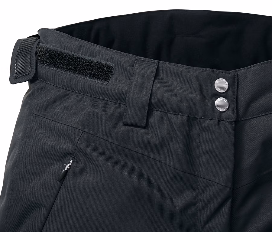 Detail einer schwarzen Skihose mit Knopfverschluss, Gürtelschlaufe und Reißverschlusstasche.