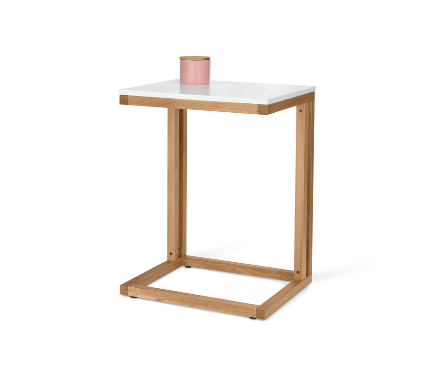 Ein C-förmiger Anstelltisch mit weißer Tischplatte und einem rosa Behälter darauf.