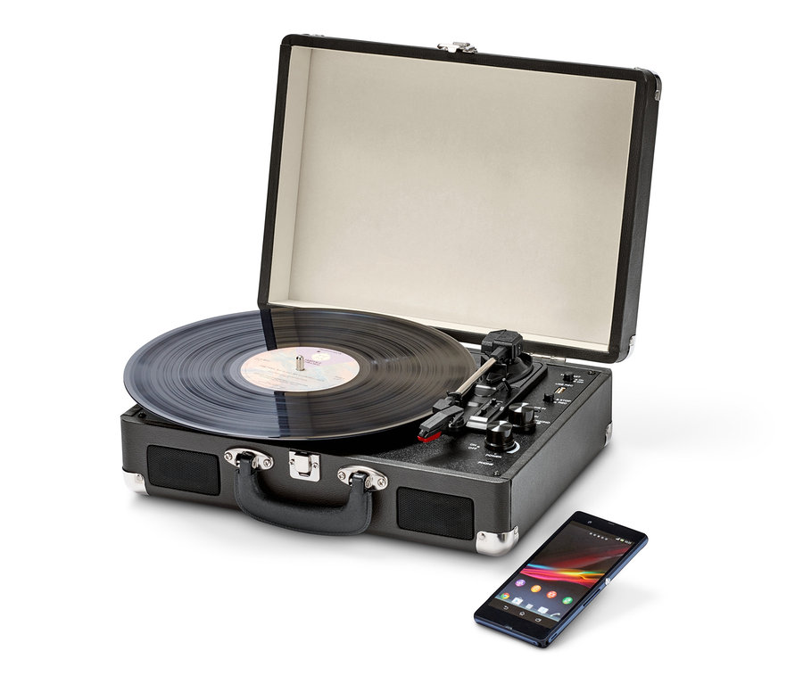 Ein schwarzer, tragbarer Retro-Plattenspieler mit Bluetooth-Funktion mit geöffnetem Deckel und Schallplatte, sowie ein Handy.
