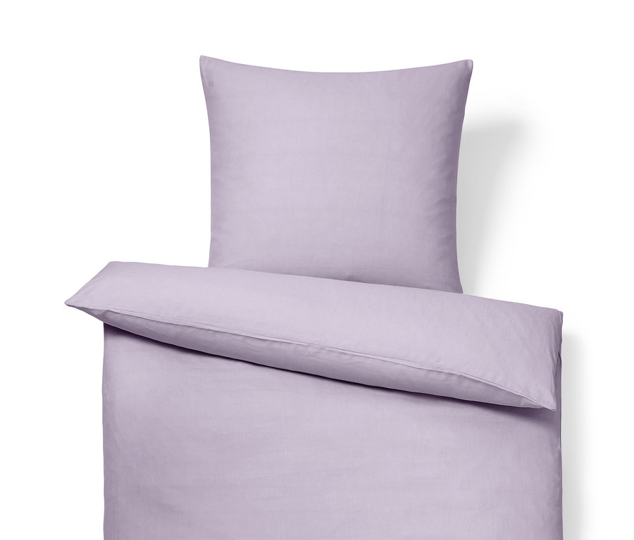 Ein Set fliederfarbener Bettwäsche aus gewaschenem Leinen: Bettlaken, Kissen und Bettdecke.