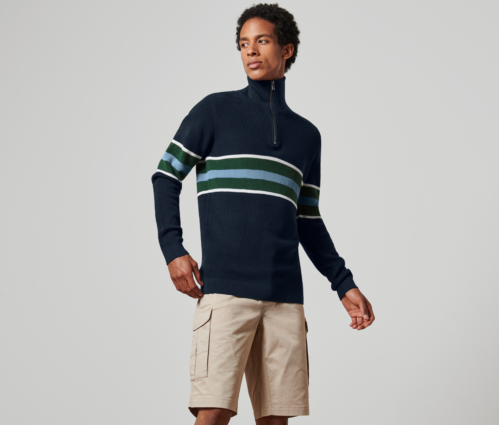 Mann trägt einen dunkelblauen Troyer-Pullover mit Streifen und Khaki-Shorts.