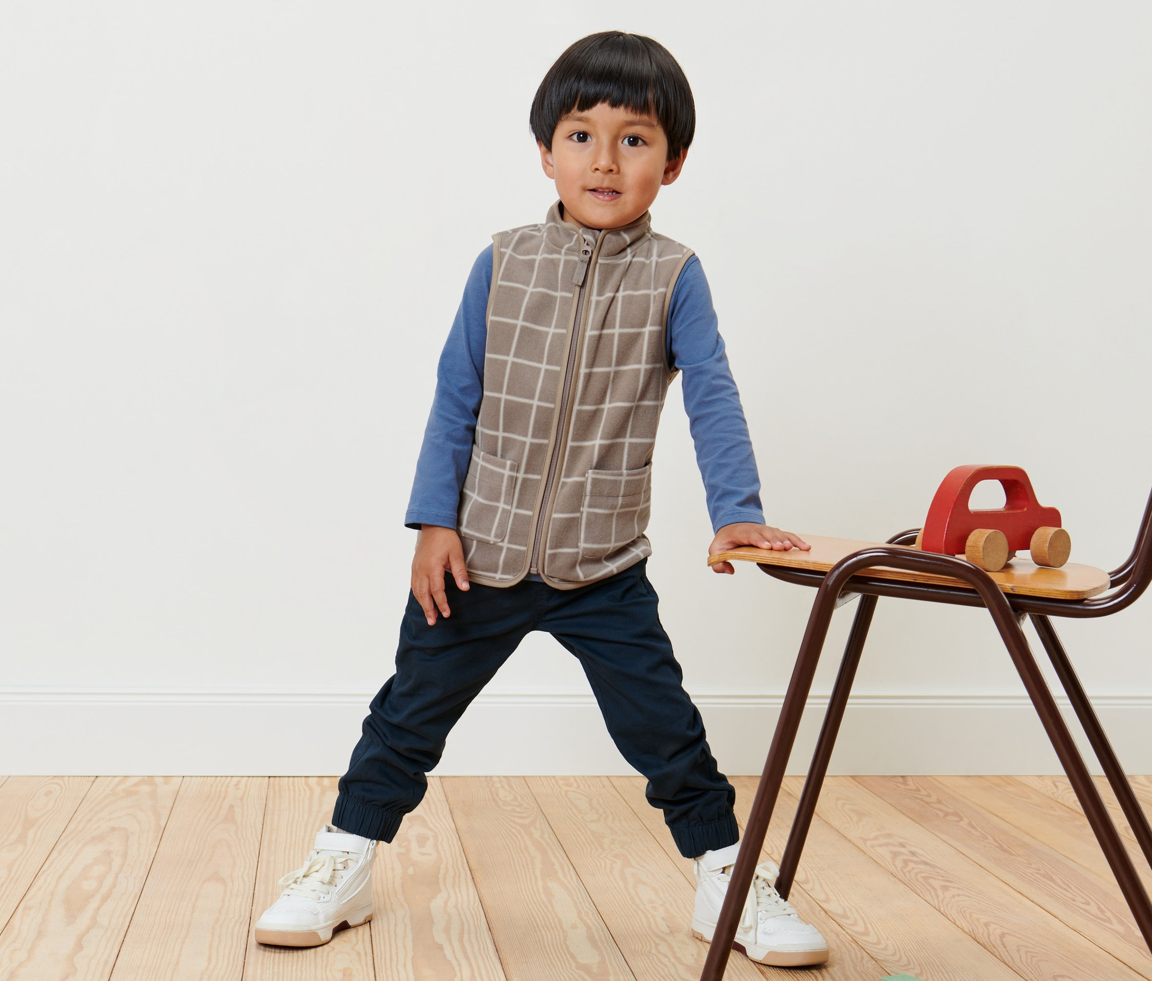 Junge steht und trägt eine Kinder-Fleeceweste mit Karo.