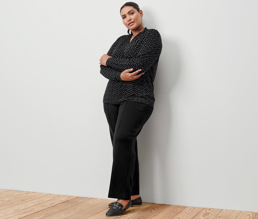 Frau posiert in schwarzer Jerseyhose mit Biese und Langarmshirt mit V-Ausschnitt, Alloverprint.
